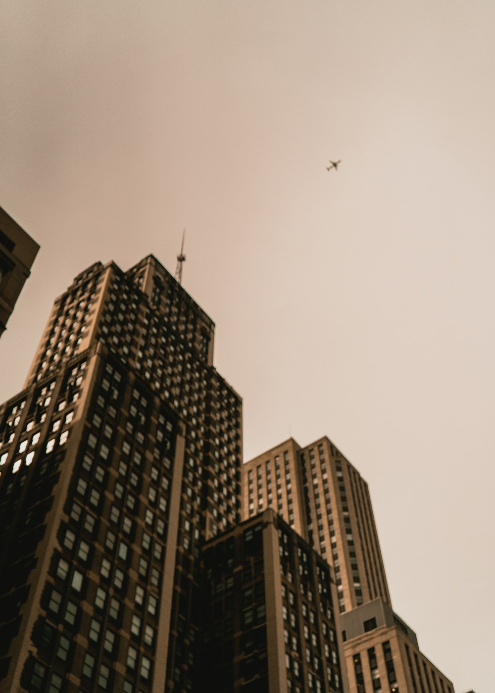 a plane is flying in the sky over some tall buildings