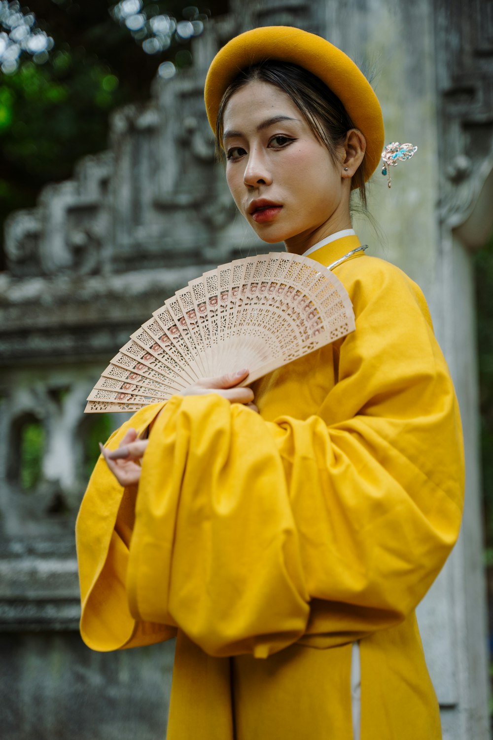 a woman in a yellow outfit holding a fan