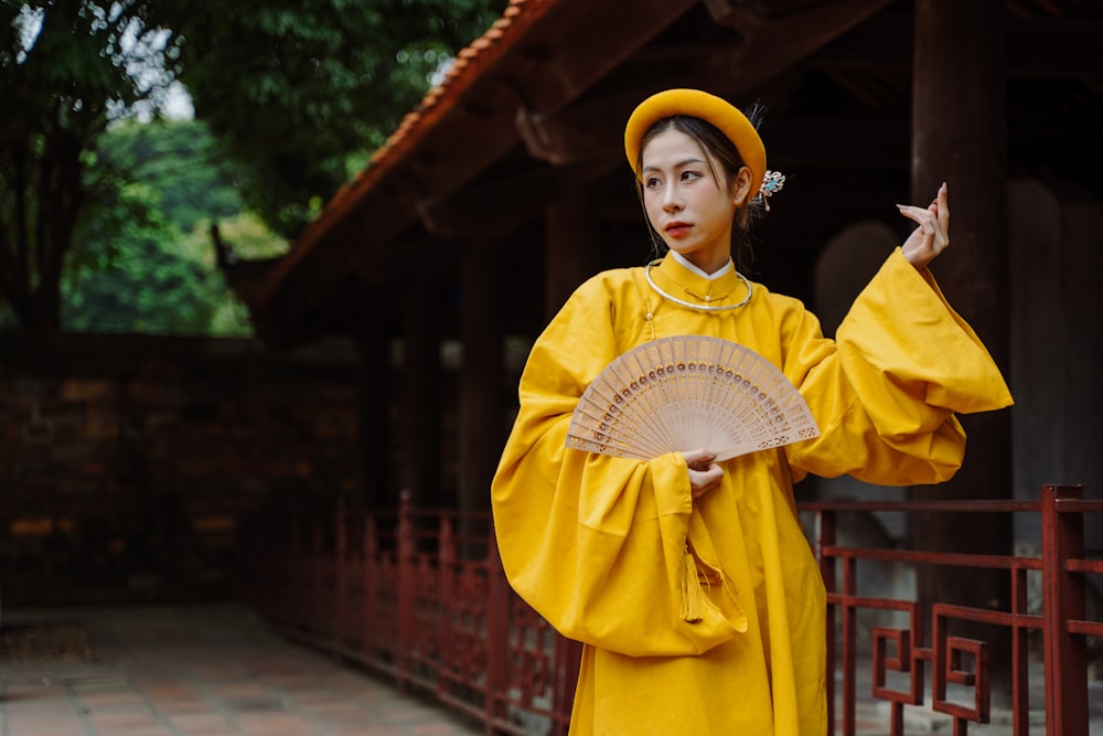 a woman in a yellow outfit holding a fan