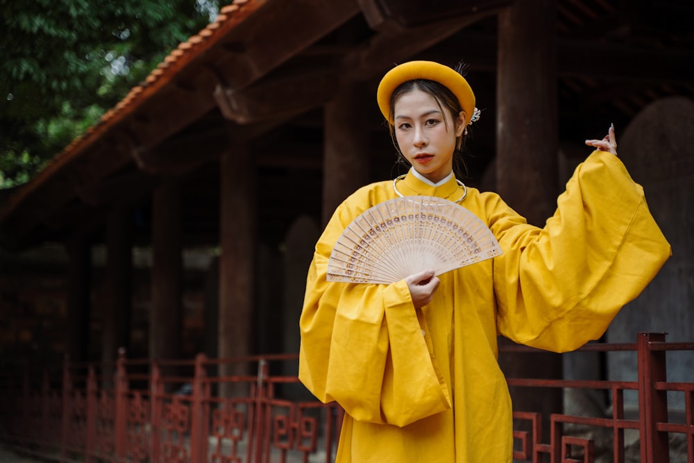 a woman in a yellow outfit holding a fan