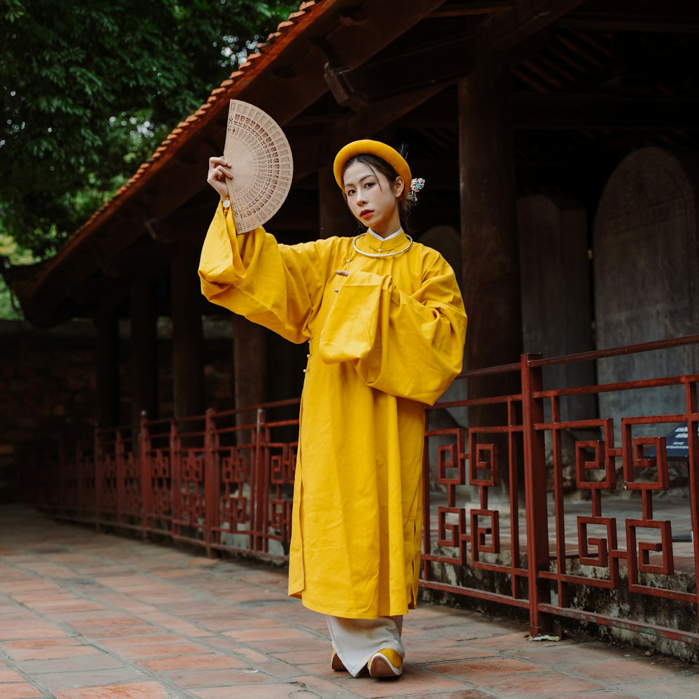 a woman in a yellow outfit is holding a fan