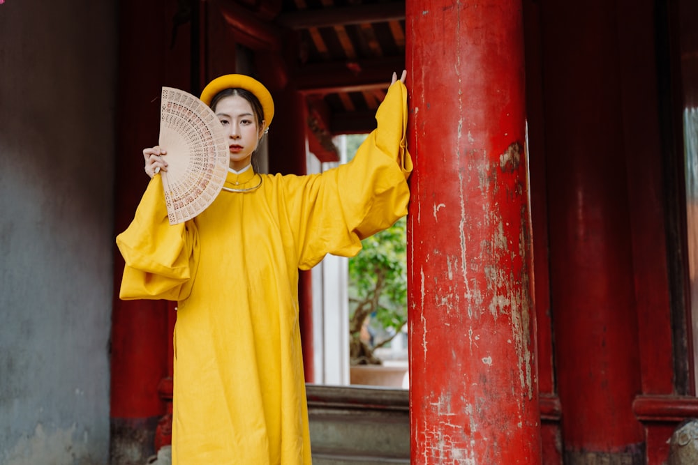 Eine Frau im gelben Outfit hält einen Fächer