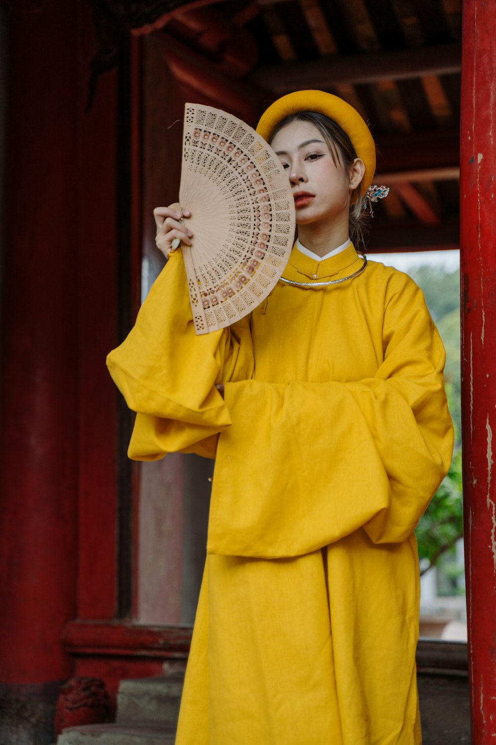 a woman in a yellow outfit holding a fan