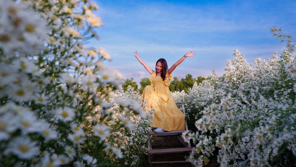 a woman in a yellow dress standing in a field of flowers