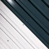 Glossy green powder-coated metal panels stacked neatly inside a factory