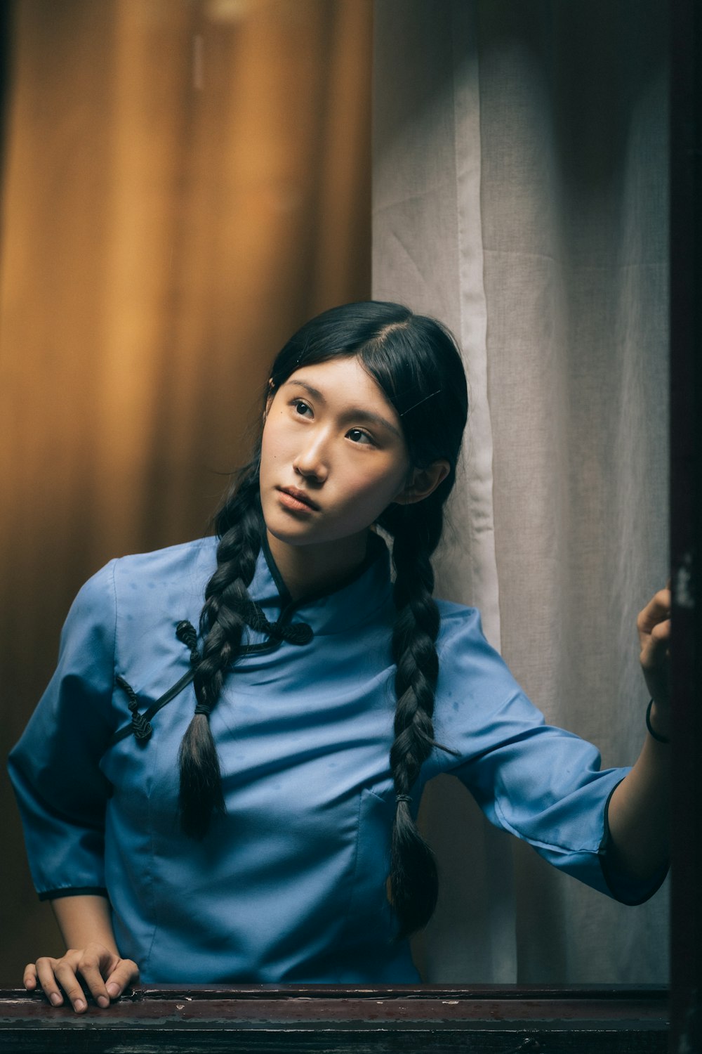 a woman with long hair standing in front of a curtain