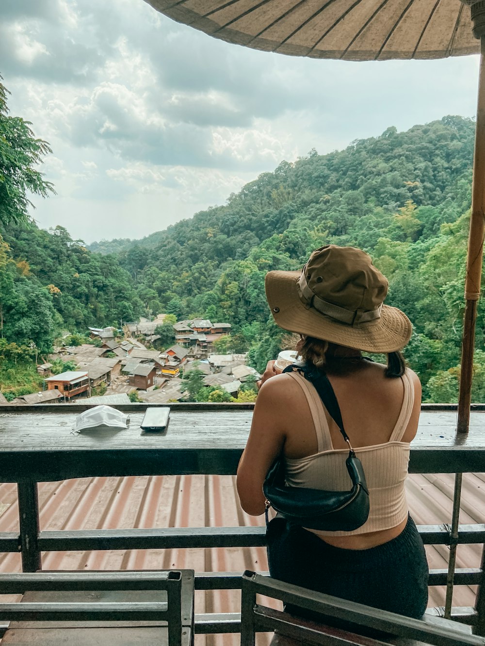 a woman in a hat looking out over a valley