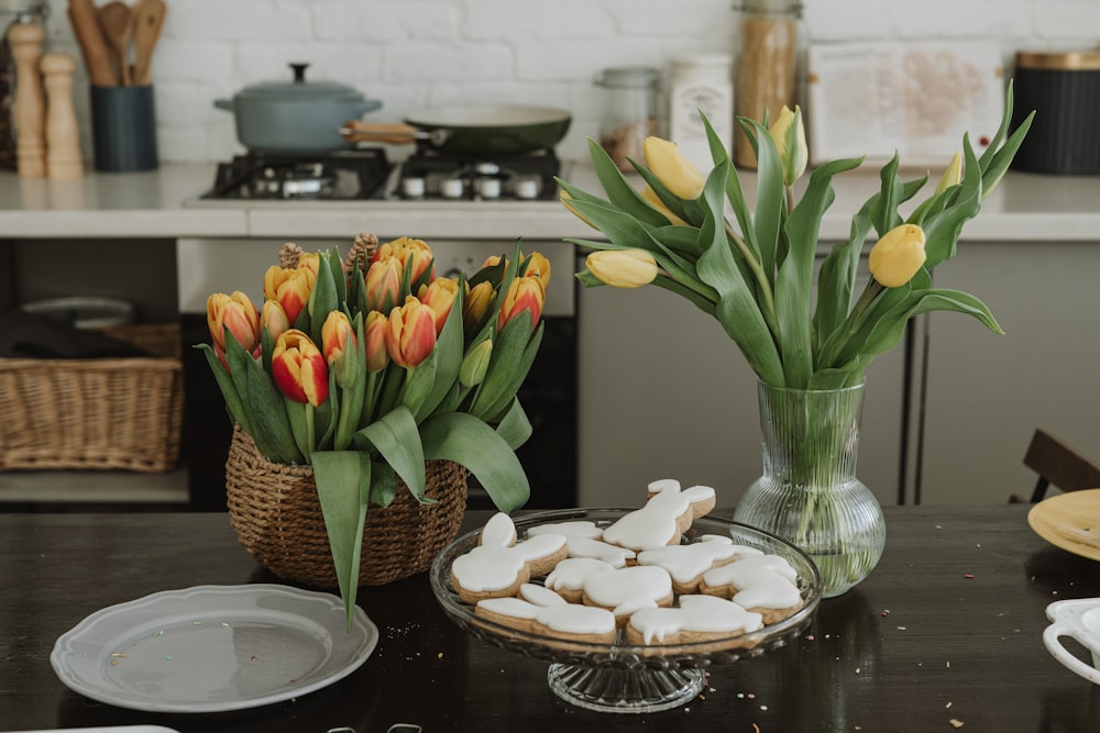 una mesa cubierta con un tazón de galletas y un jarrón de flores