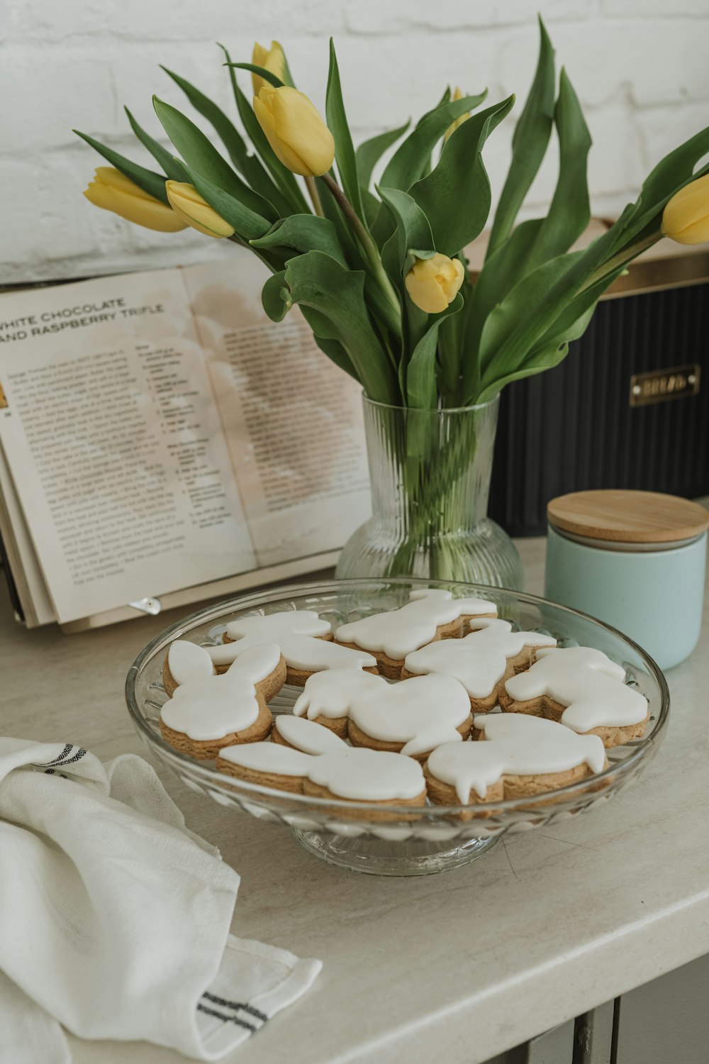 a bowl of cookies on a table next to a vase of tulips