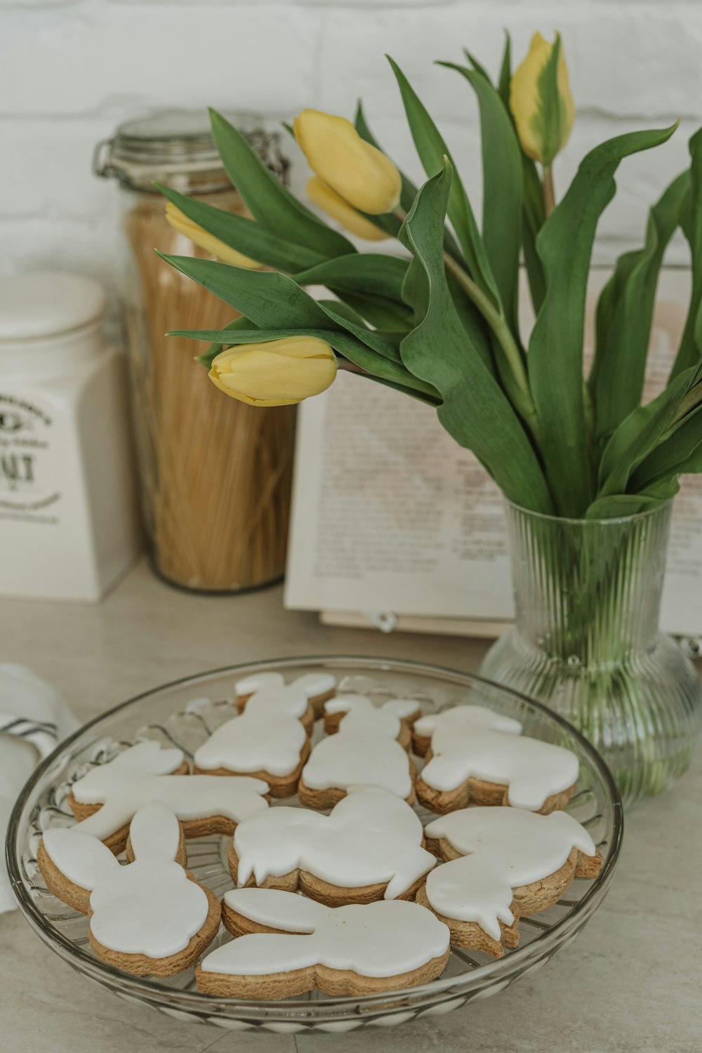 Un plato de galletas sentado en una mesa junto a un jarrón de tulipanes
