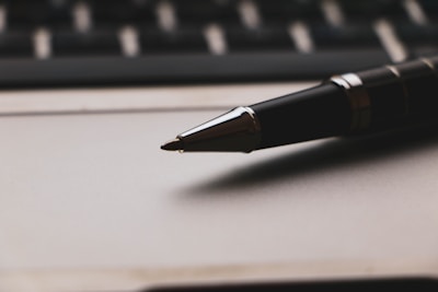 a pen sitting on top of a paper next to a keyboard