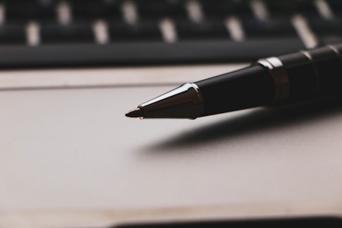 a pen sitting on top of a paper next to a keyboard