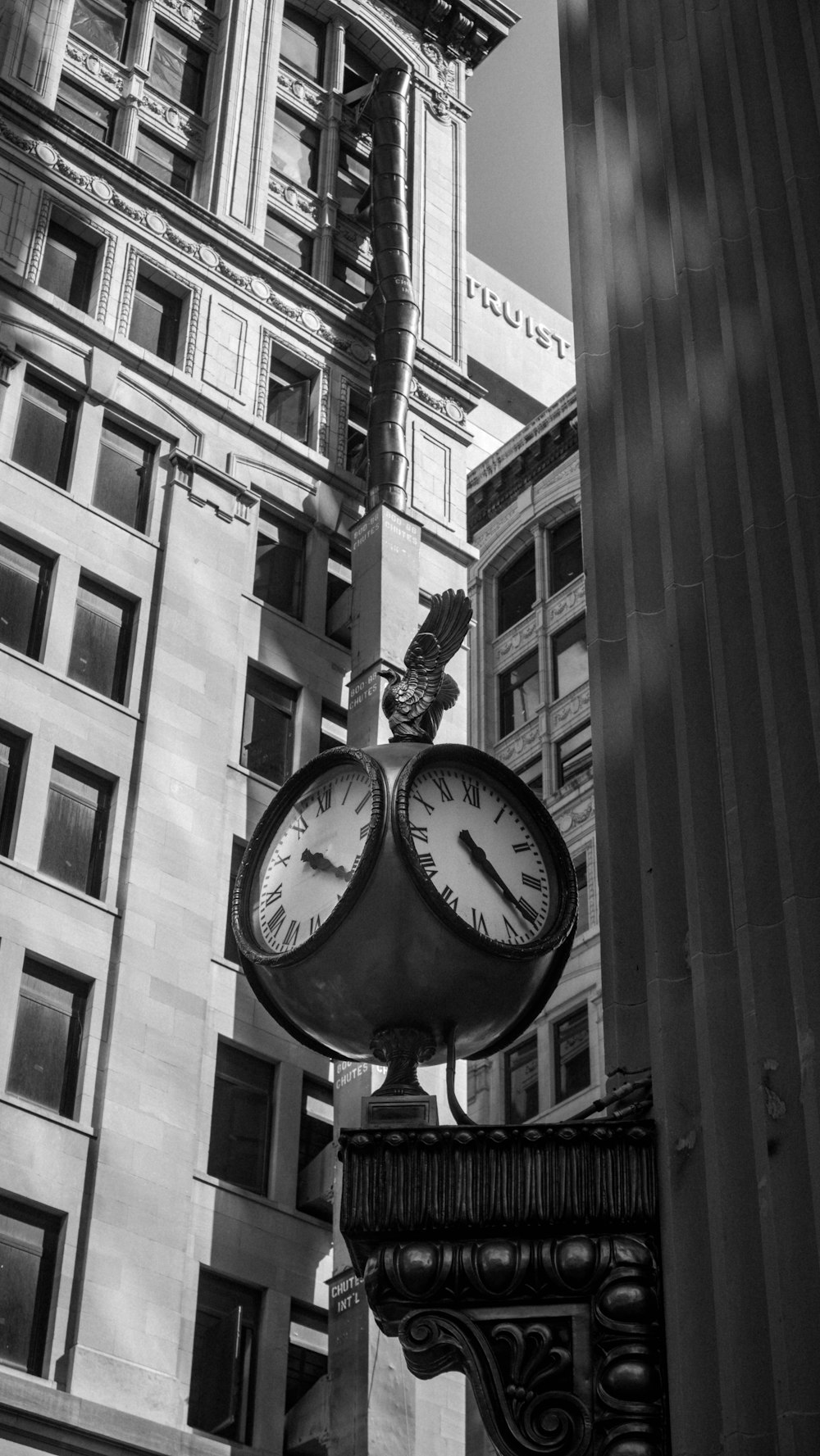 a black and white photo of a clock on a pole