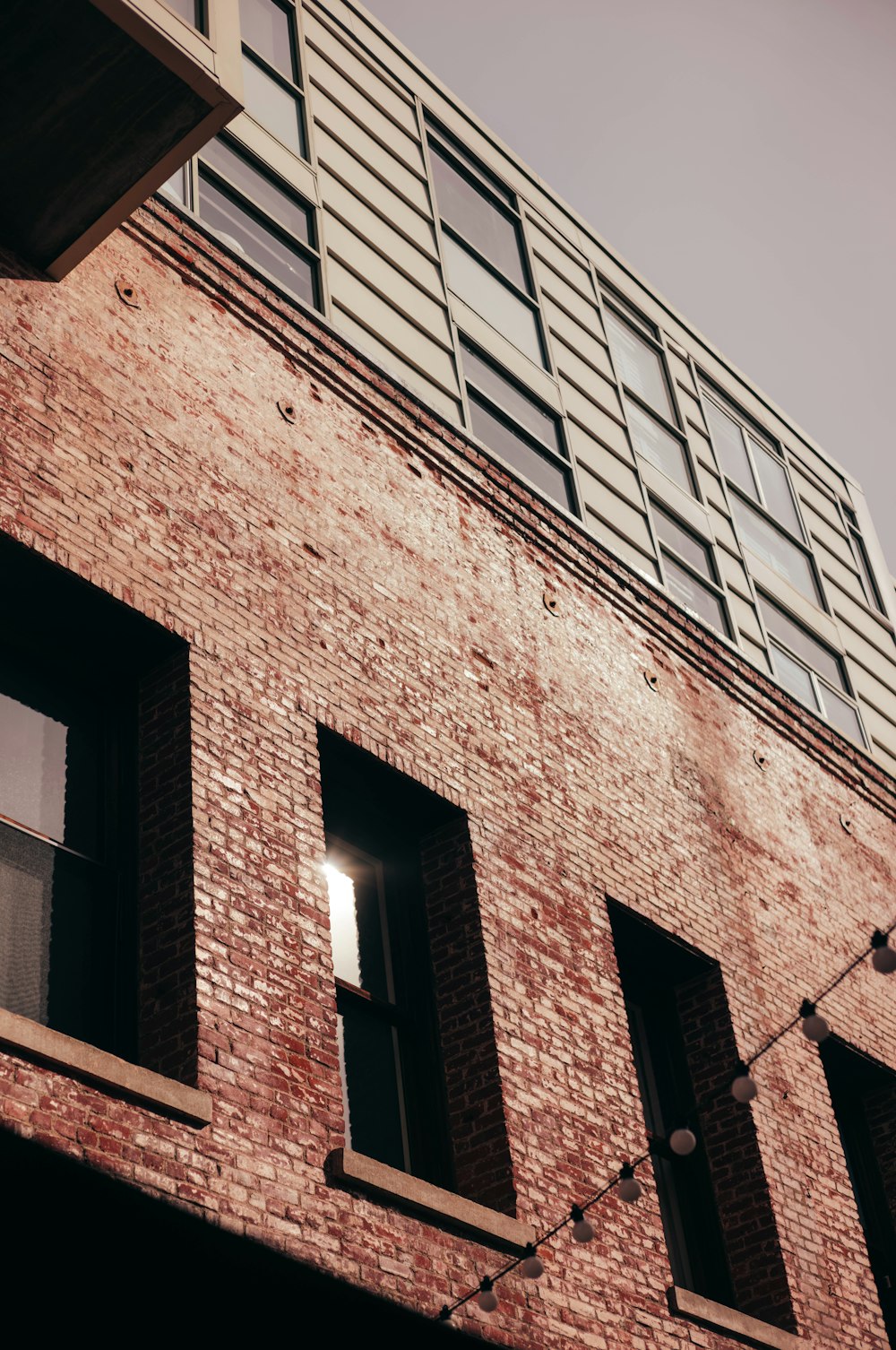 a tall brick building with windows and a sky background