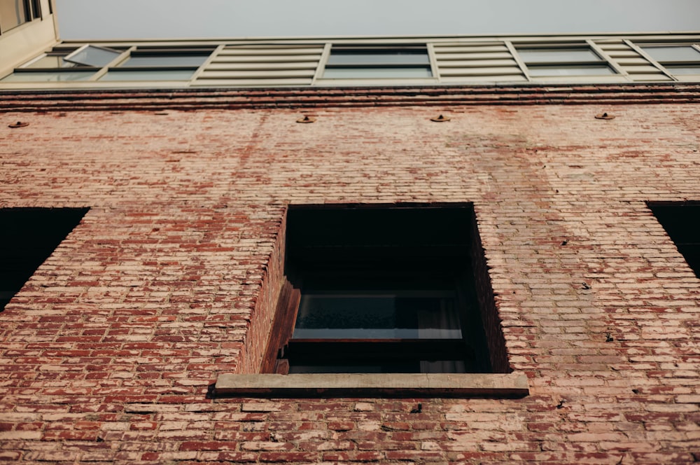 a brick building with two windows and a sky background