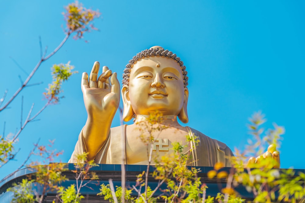 a golden buddha statue sitting on top of a lush green field