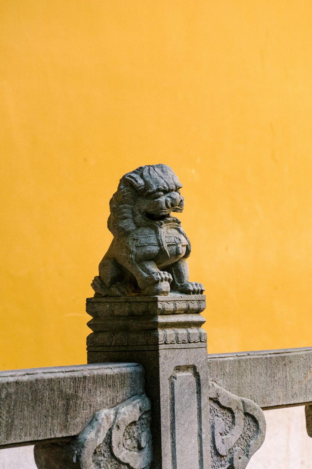 a statue of a lion sitting on top of a fence