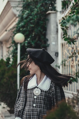 A model wearing a classic beret outdoors, with autumn leaves in the background.