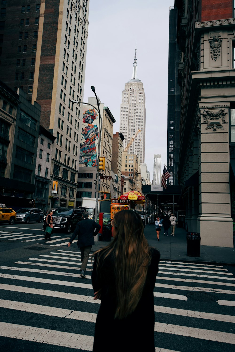 a woman walking across a cross walk in a city