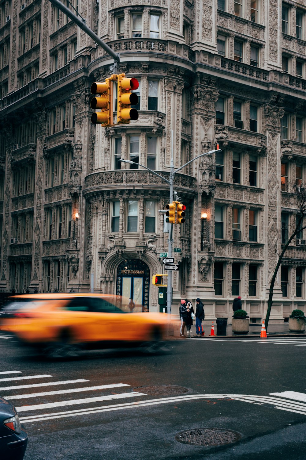 a yellow car driving down a street next to a tall building