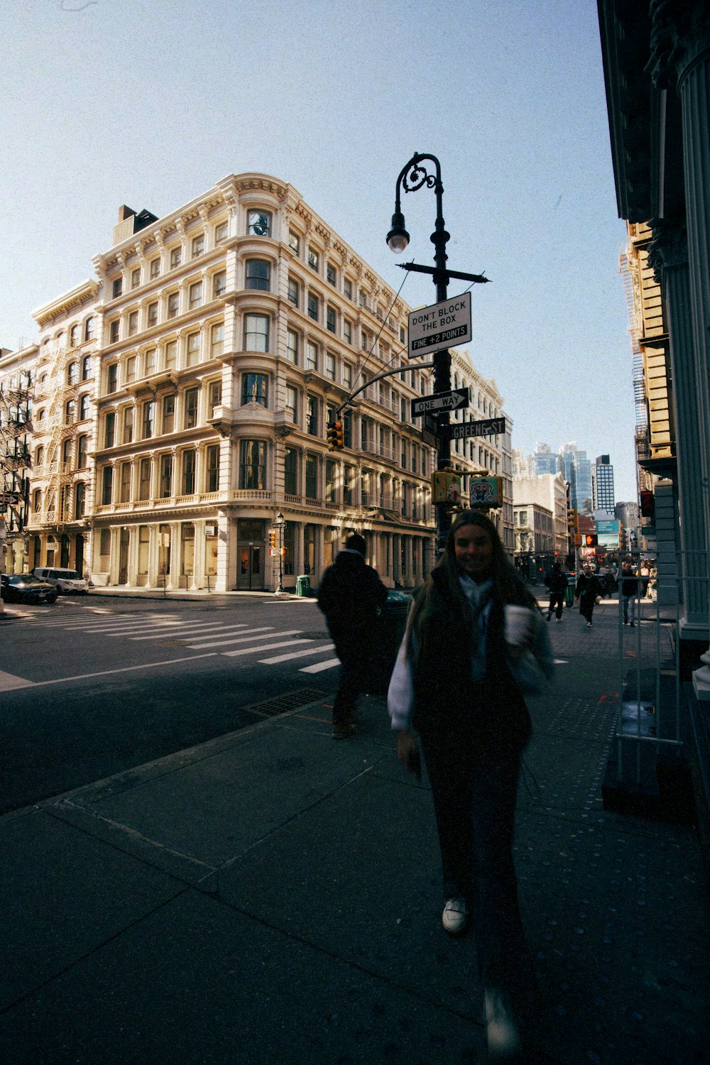 a woman walking down a street next to a tall building