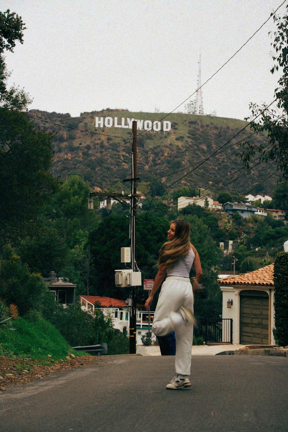 a woman walking down a street in front of a hollywood sign