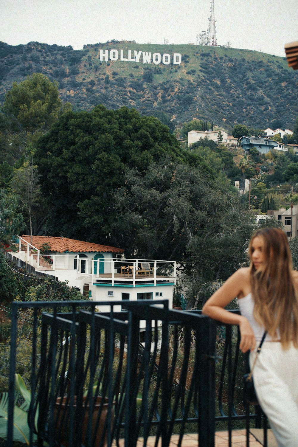 a woman standing on a balcony looking at the hollywood sign