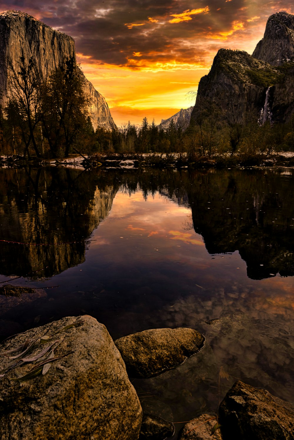 a beautiful sunset over a mountain lake with rocks in the foreground