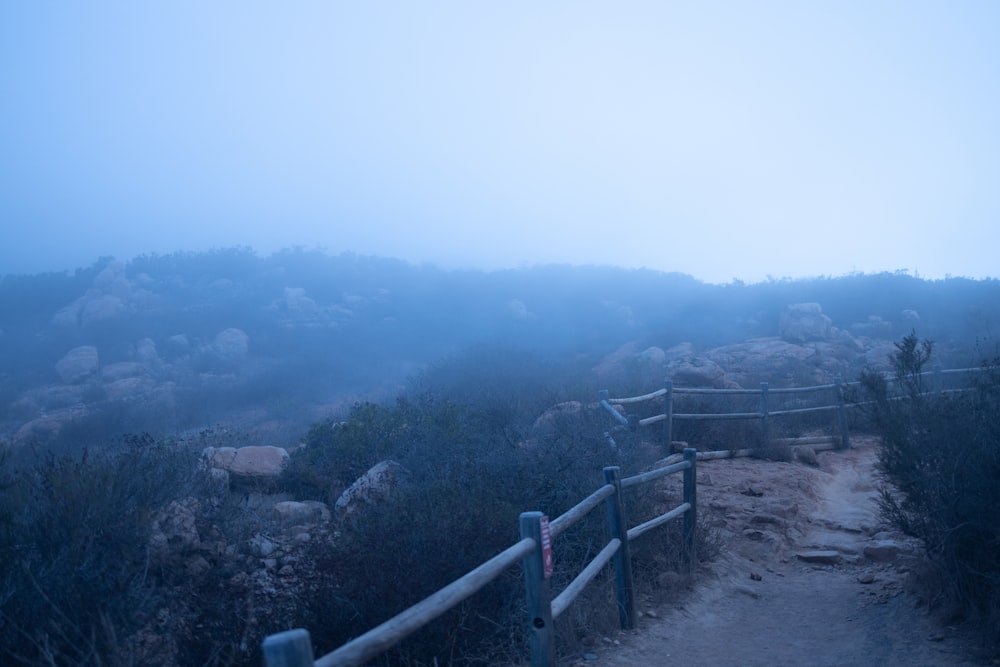 a foggy mountain trail with a wooden fence