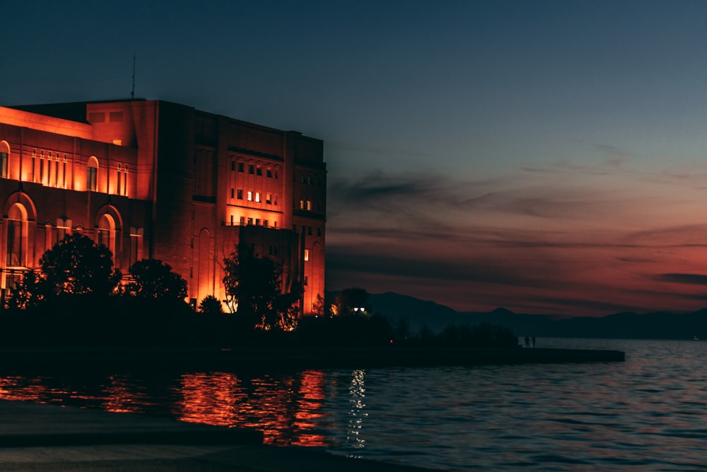 a building is lit up at night by the water