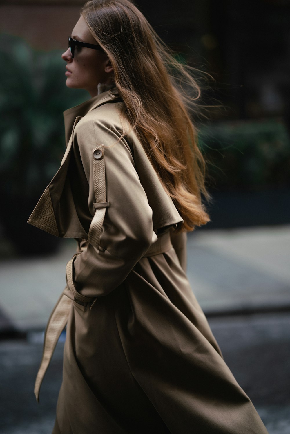 a woman walking down the street in a trench coat