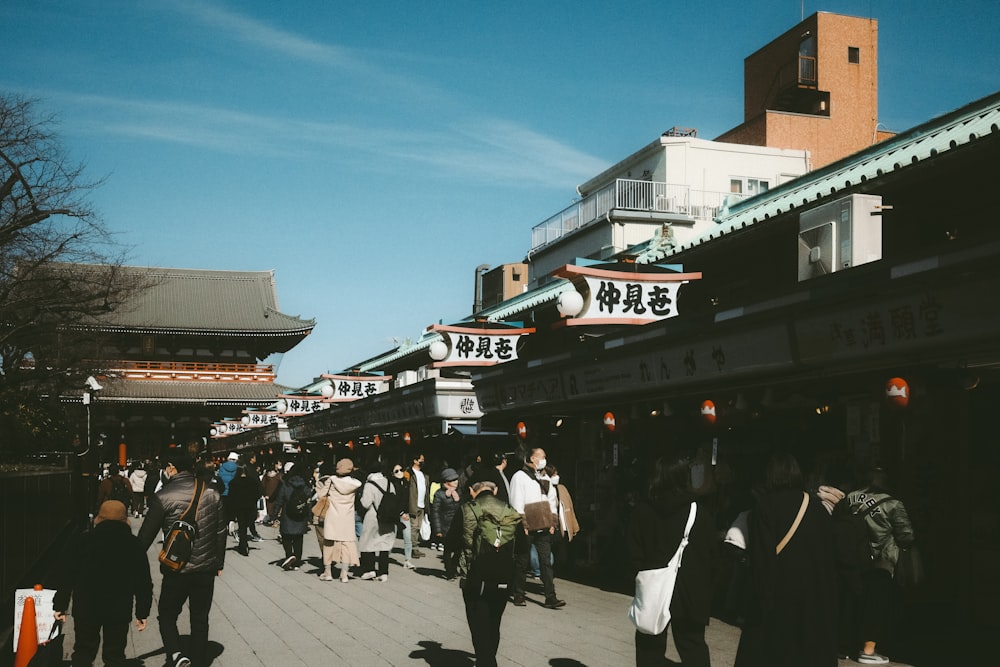 a group of people walking down a street next to tall buildings