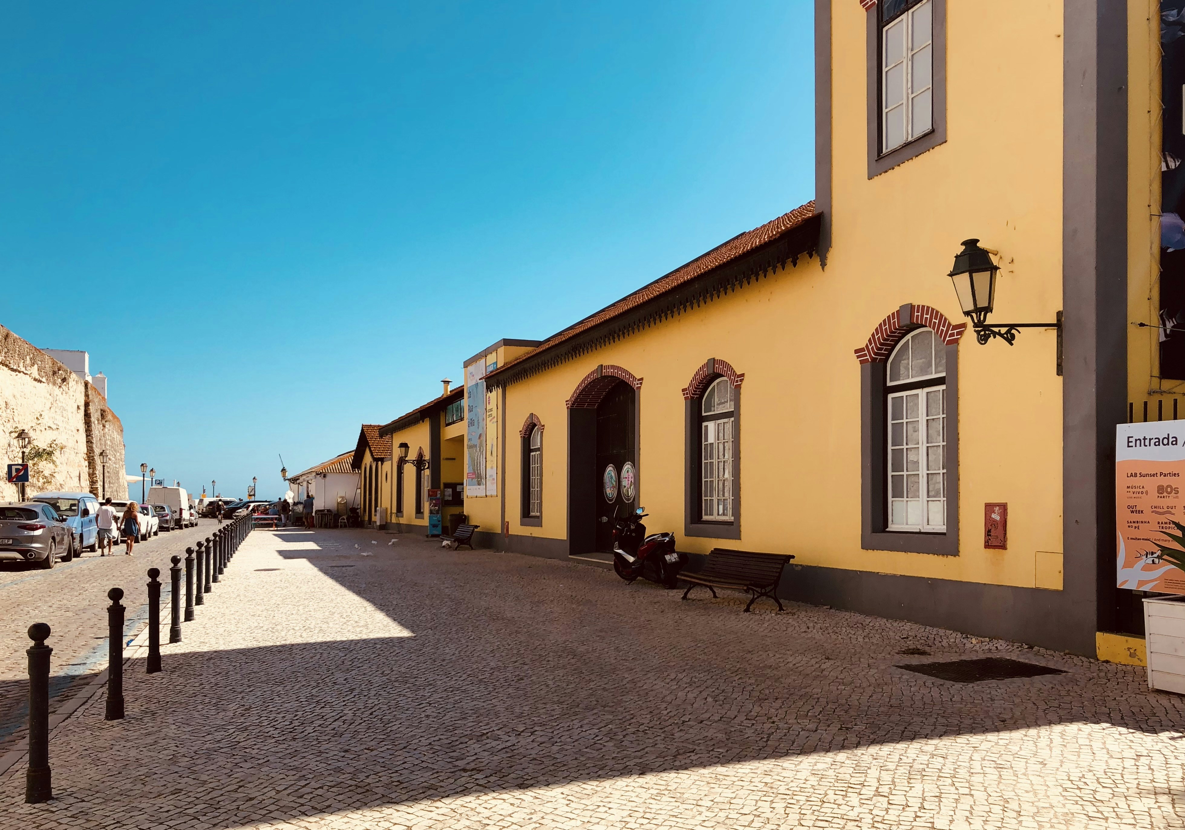 A charming cobblestone street lined with traditional yellow and white buildings in the historical center of Faro