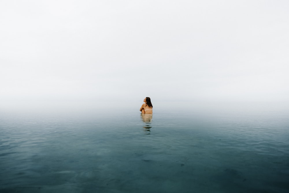 a woman standing in the middle of a body of water