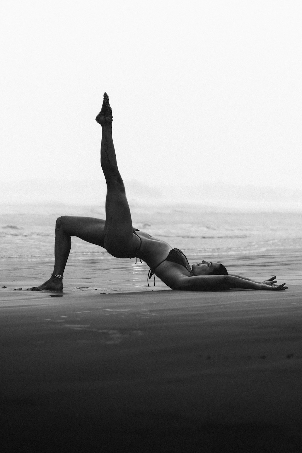 a woman doing a handstand on the beach