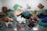 A diverse collection of colorful minerals and crystals displayed on a reflective surface, featuring a wide array of shapes and textures, with hues ranging from deep reds and blues to greens, browns, and whites.