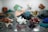 A diverse collection of colorful minerals and crystals displayed on a reflective surface, featuring a wide array of shapes and textures, with hues ranging from deep reds and blues to greens, browns, and whites.