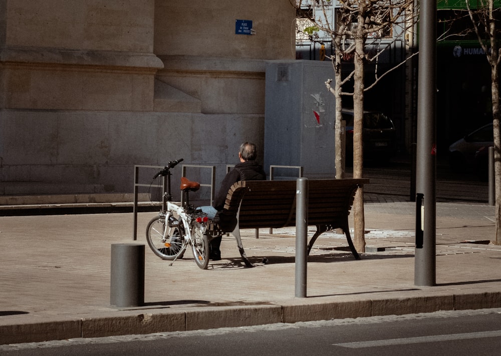 a man sitting on a bench next to a bike