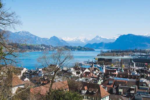 Panorama de uma cidade suíça com montanhas ao fundo em um dia claro e ensolarado.