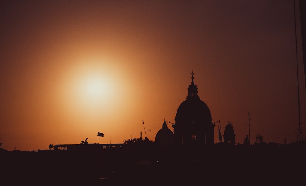 the sun is setting behind a building with a dome