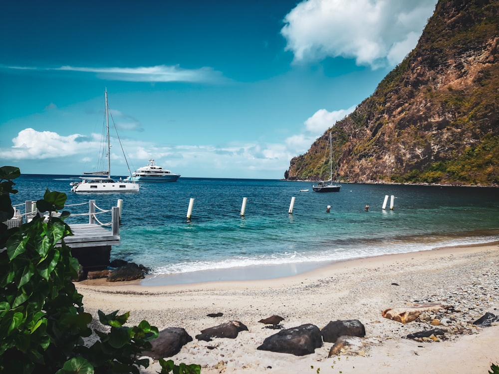 a beach with boats in the water and a mountain in the background