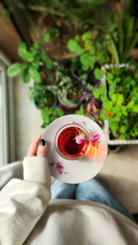 A serene woman enjoying a morning tea in a sunlit room surrounded by plants.