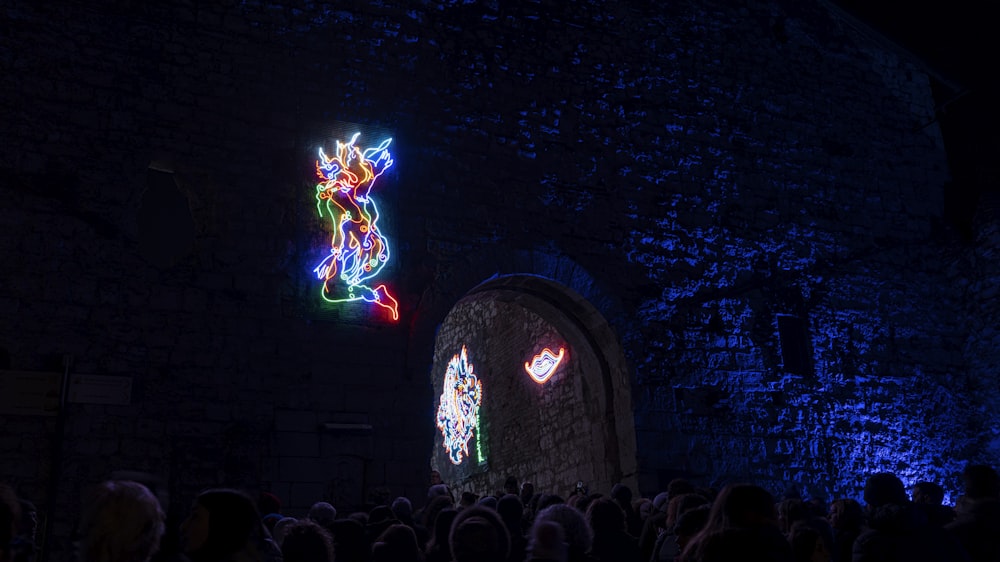 a group of people standing around a building with lights on it