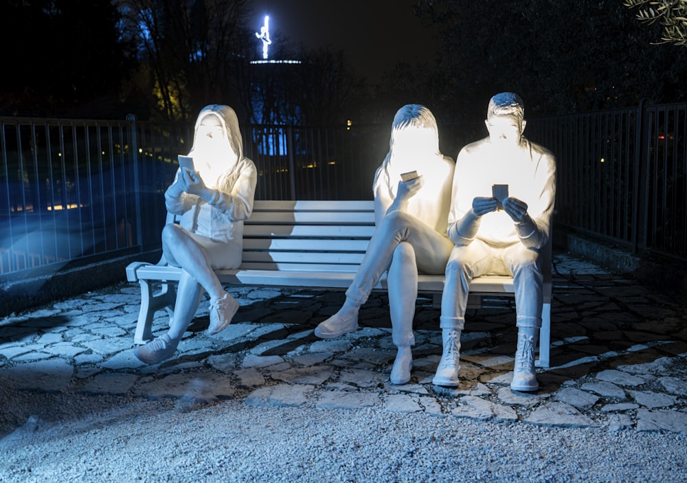 a couple of people sitting on top of a white bench