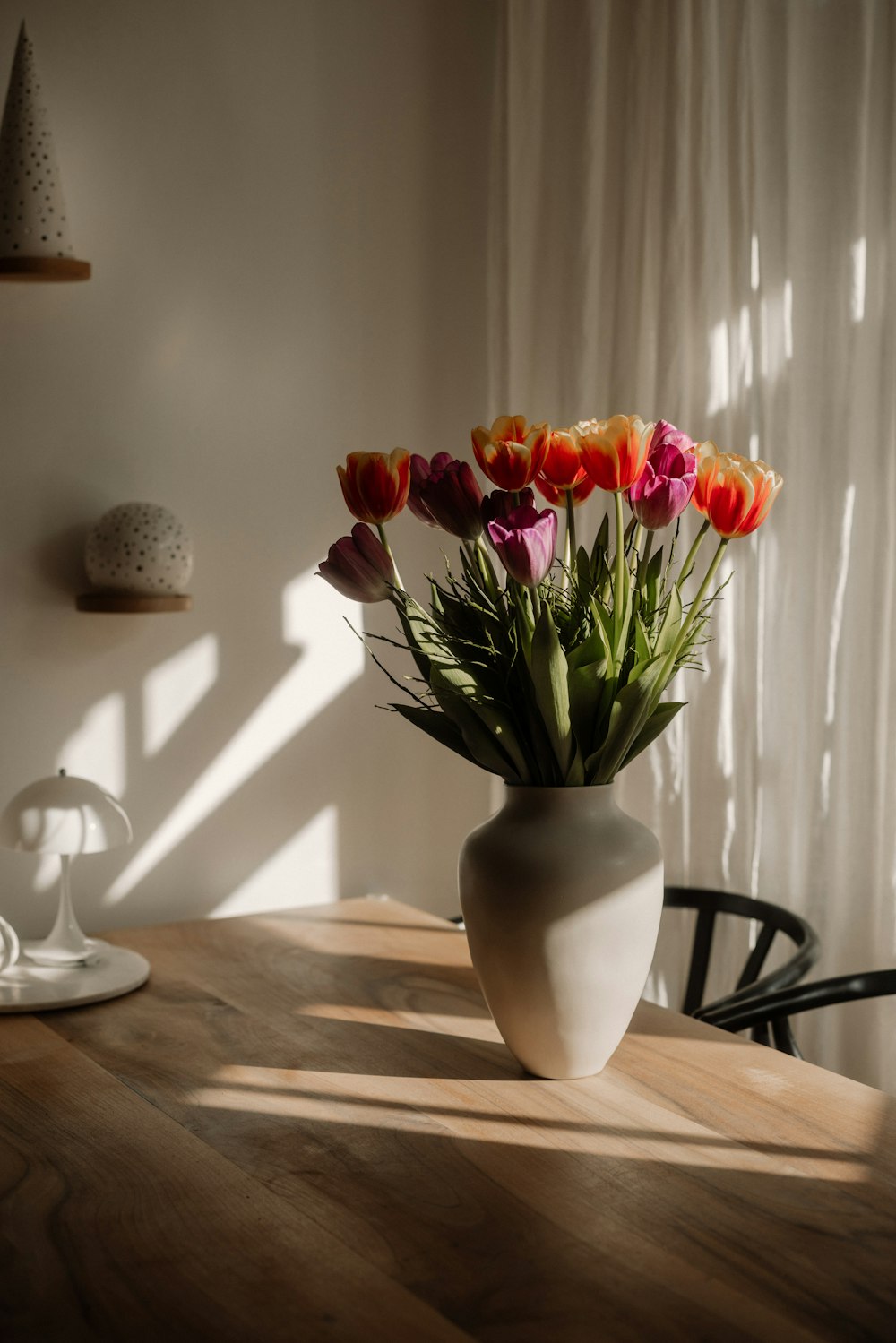 a white vase filled with lots of flowers on top of a wooden table