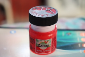 Close-up of a vintage-style jar of roqvel hair gel with Moroccan patterns in the background