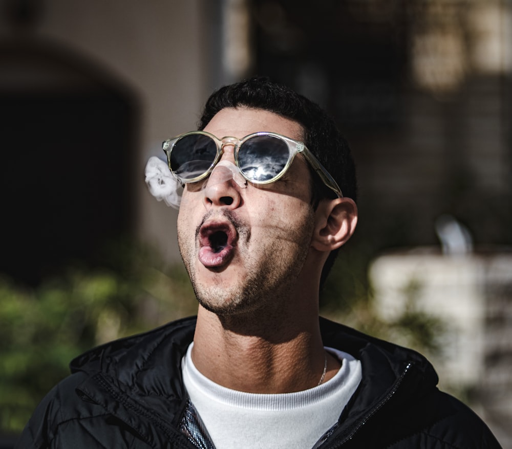 Un uomo con gli occhiali da sole che spegne una sigaretta