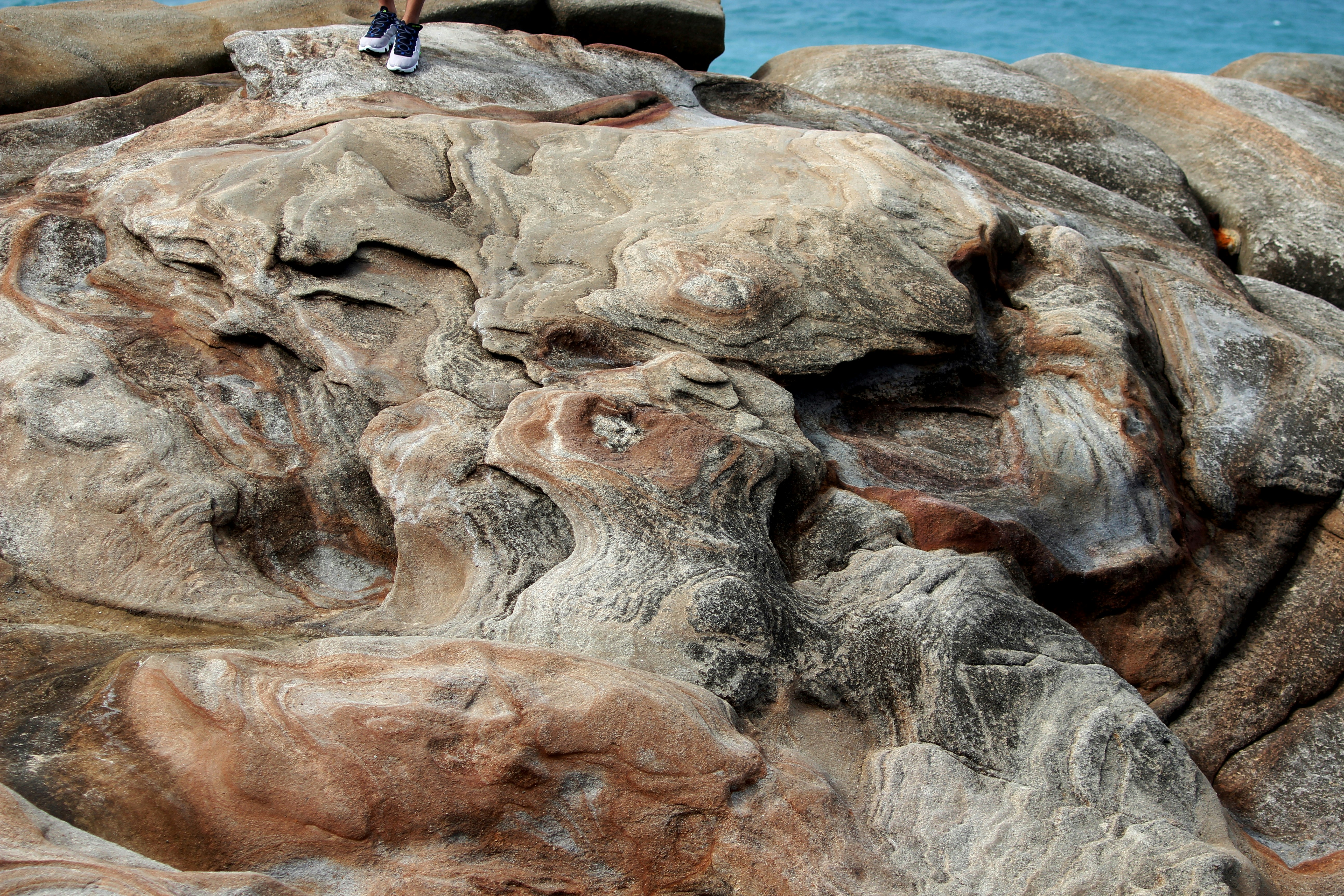 une personne debout au sommet d’un rocher au bord de l’océan