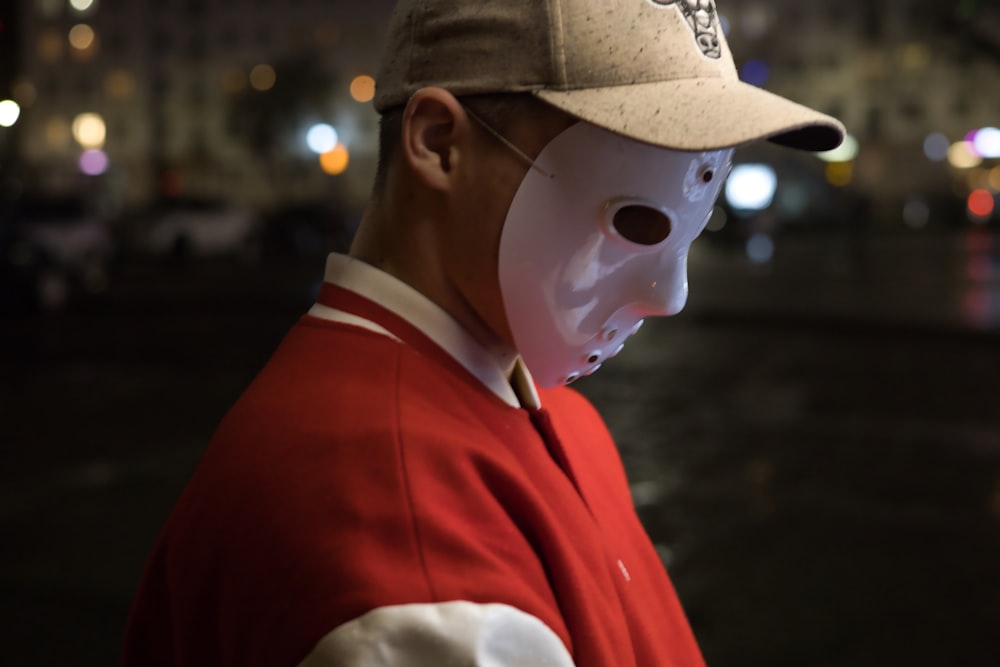 Un homme portant un masque blanc et une veste rouge