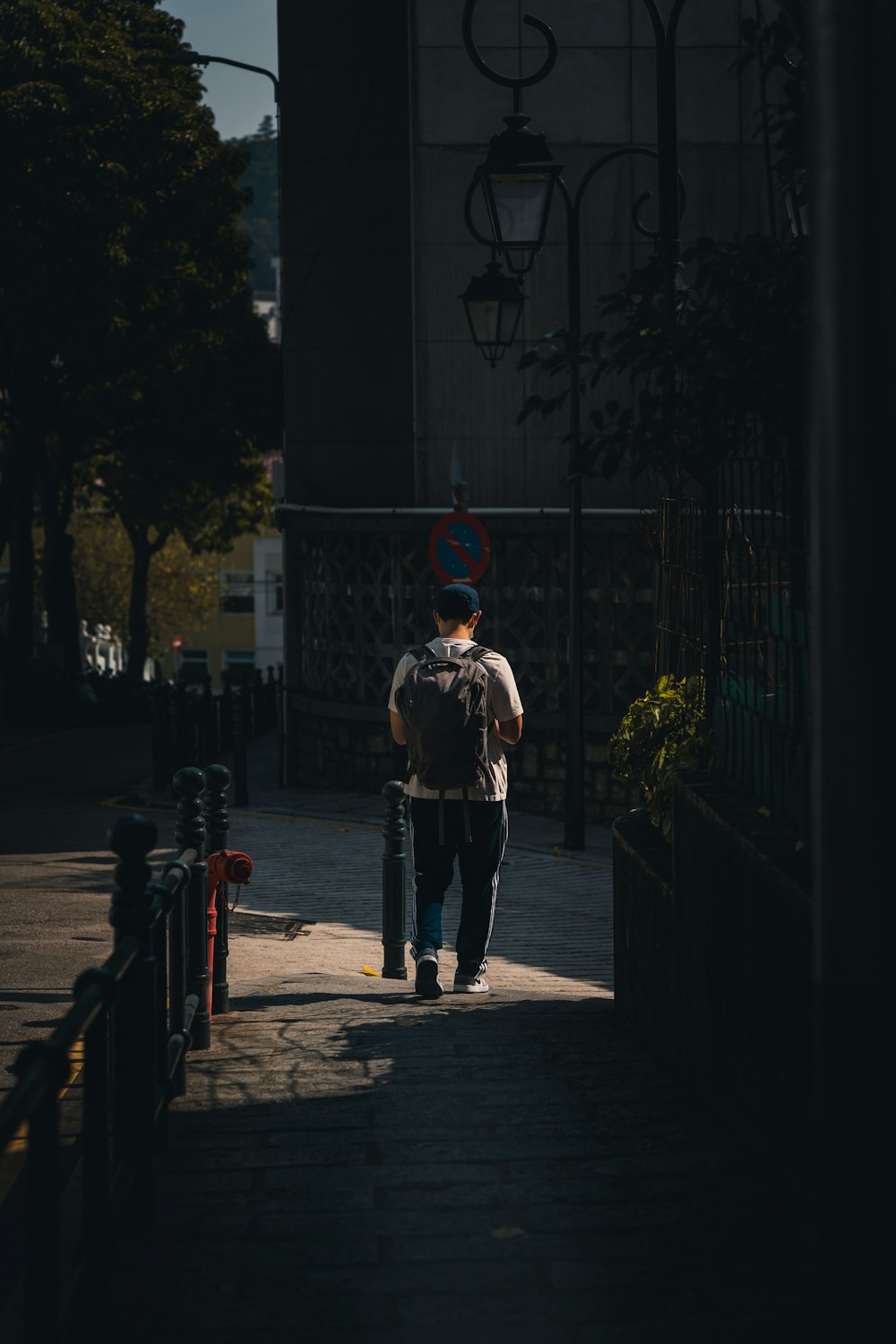 a man walking down a sidewalk with a backpack